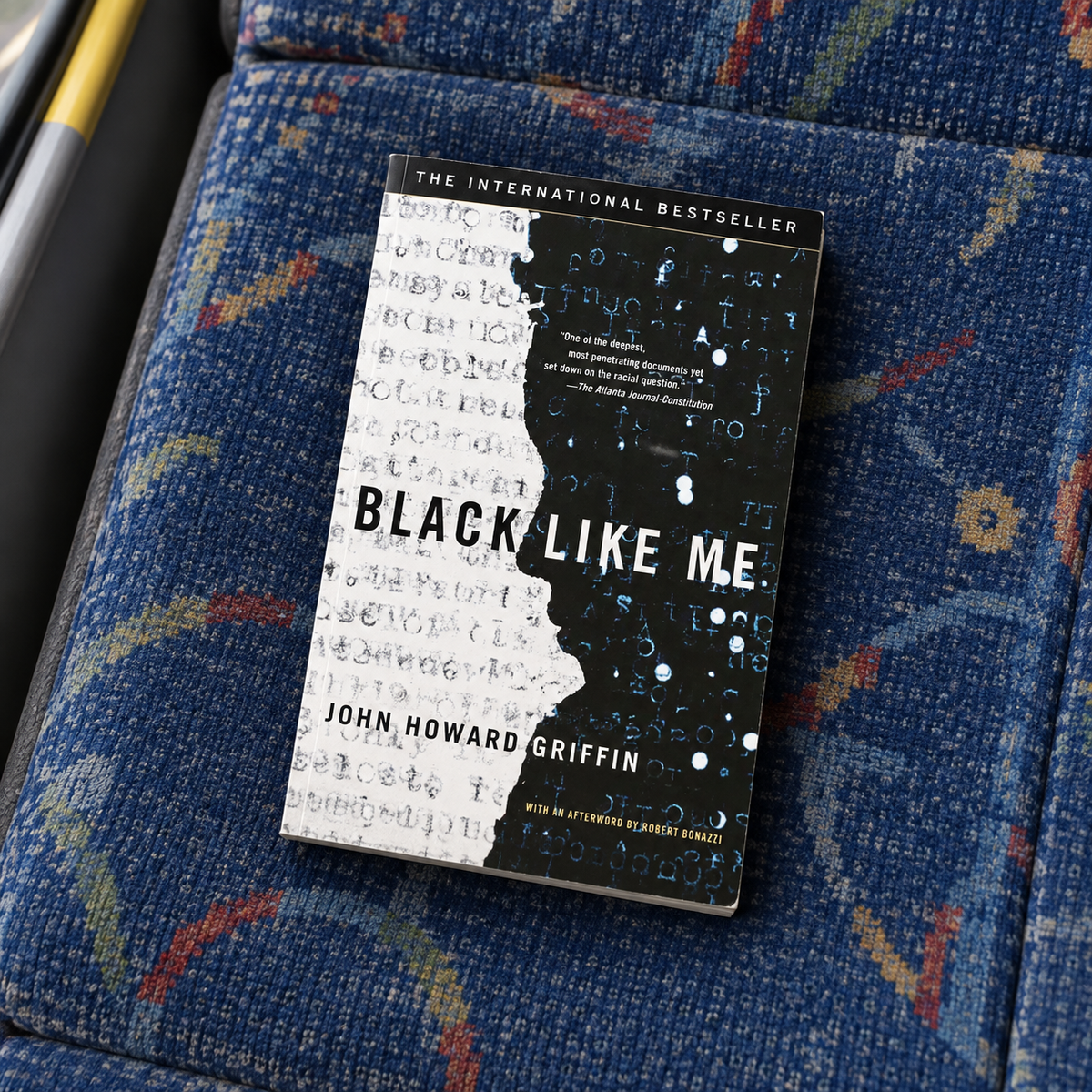 Black Like Me paperback by John Howard Griffin resting on a blue bus seat