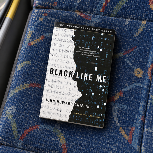 Black Like Me paperback by John Howard Griffin resting on a blue bus seat